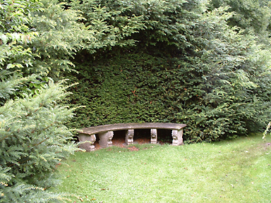 Die Natursteinbank in der Eibennische liegt in einem ruhigen Winkel des Gartens und bietet einen Ort des Rückzugs, Privatgarten, Niedersachsen